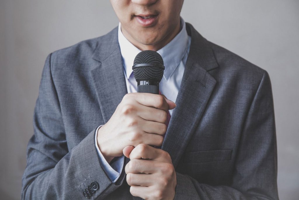 Foto de un joven hablando por un micrófono.